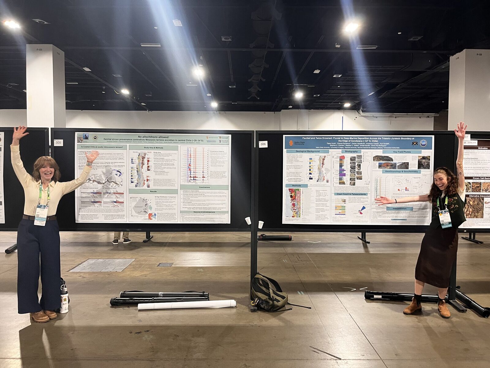 Amarissa Cramer and Tiana Hursh, arms raised in celebration, standing at either end of their two research posters in the GSA Connects poster hall
